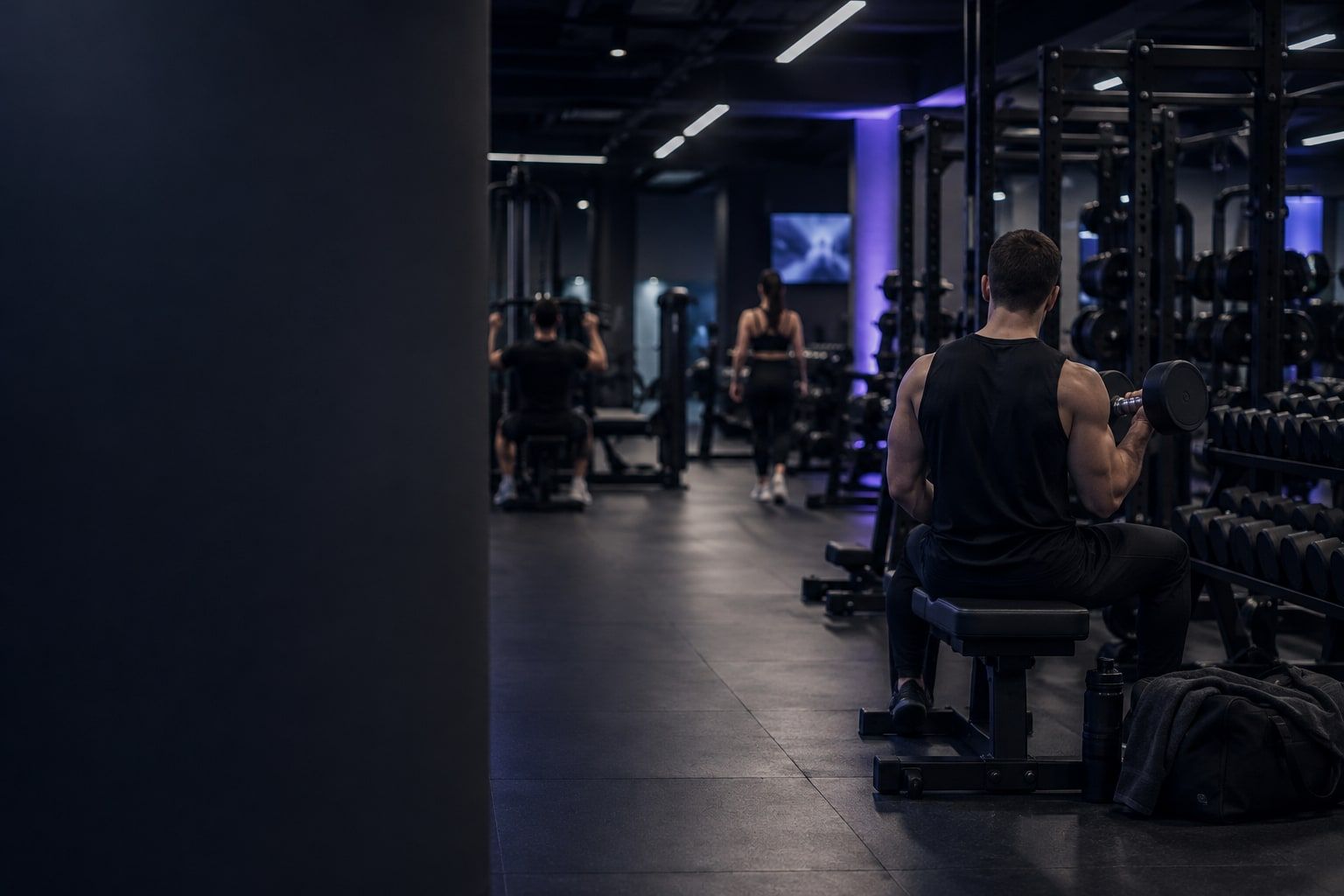 An evening gym floor: people training, seen from behind.